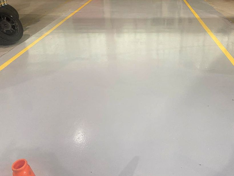 Grijze epoxyvloer met gele belijning in een werkplaats