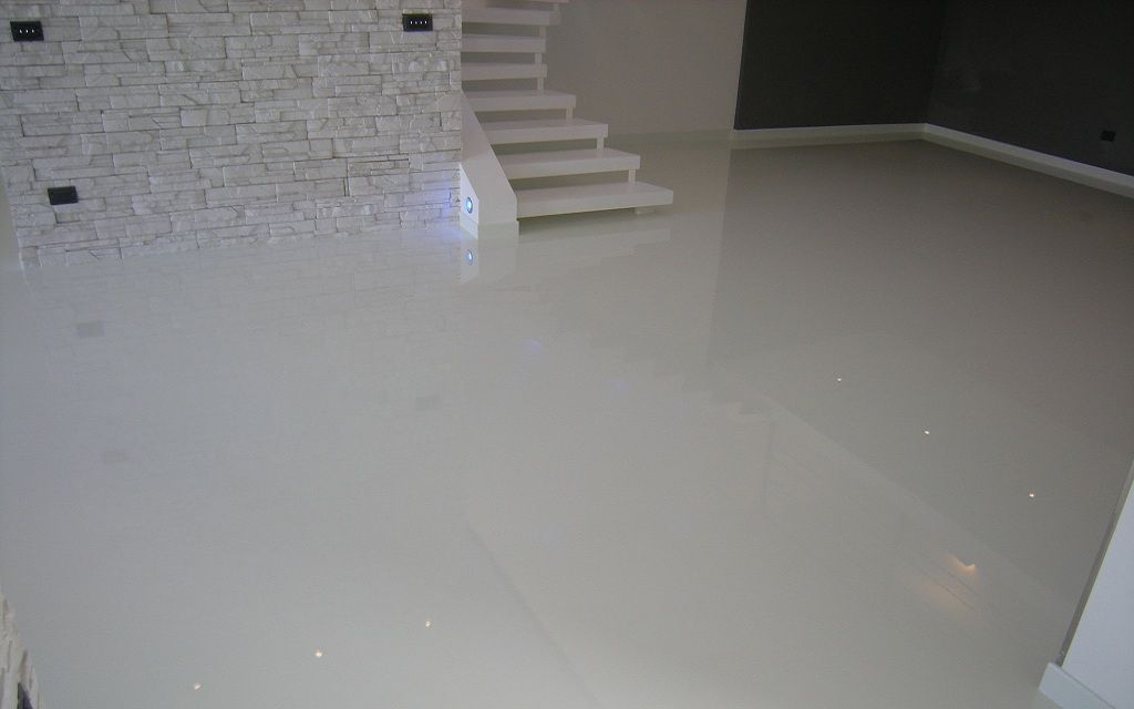 Witte, glanzende gietvloer in een woning met een trap